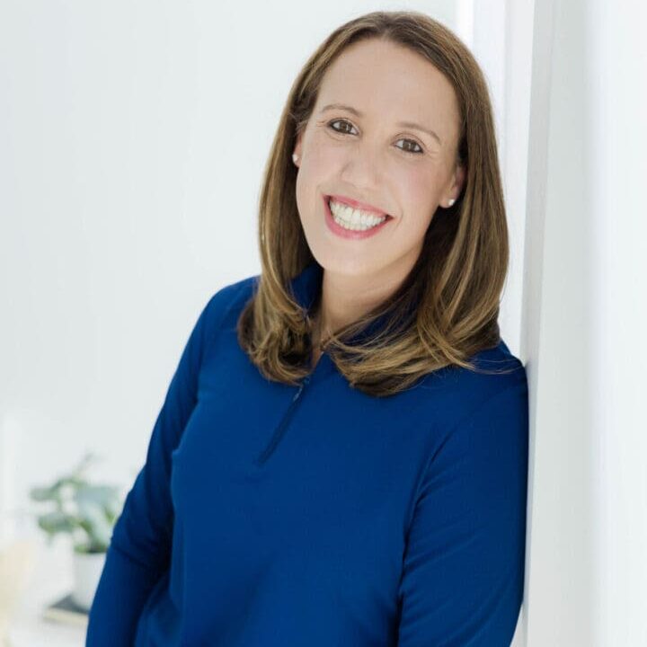 A woman in blue shirt smiling for the camera.